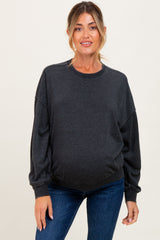 woman wearing a dark grey oversized maternity sweatshirt and showing her baby bump