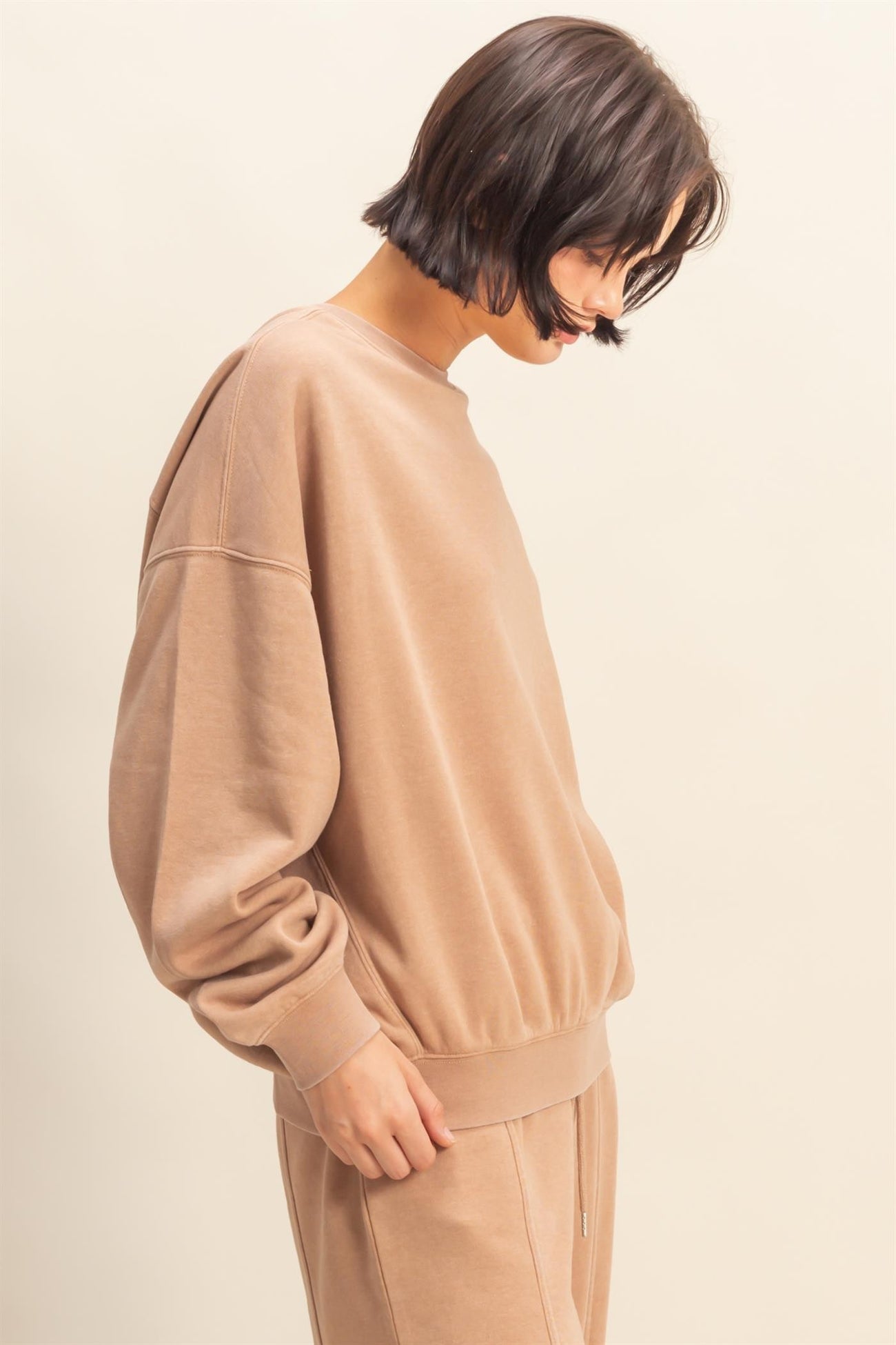 woman wearing a beige oversized sweatshirt with a relaxed fit and elasticized hem