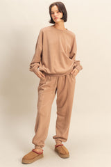 woman wearing a beige oversized sweatshirt and matching sweatpants, paired with brown slip-on shoes