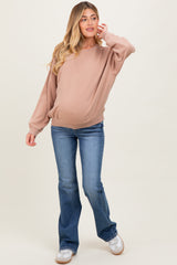 woman wearing a beige maternity sweatshirt with a relaxed fit and baby bump, paired with flared blue jeans
