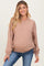 woman wearing a brown maternity sweatshirt and showing her baby bump while smiling