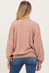 woman wearing a relaxed fit blush pink maternity sweatshirt from the back, paired with blue jeans