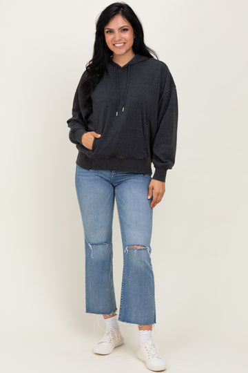 woman wearing a dark gray oversized hoodie paired with light blue flared jeans and white sneakers