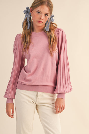 woman wearing a pink long sleeve sweater with puffed sleeves and cream-colored pants