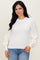 woman wearing a cream-colored sweater with puffed sleeves paired with blue jeans