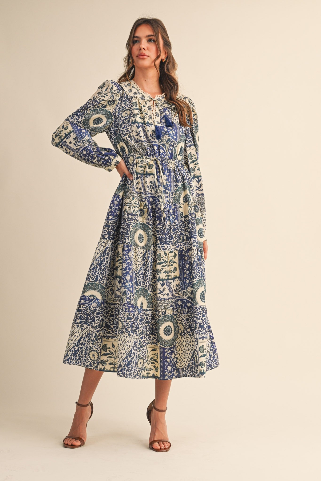 woman wearing a long sleeve blue and cream floral print maxi dress with a fitted bodice and tiered skirt