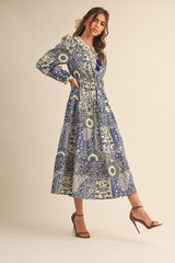 woman wearing a long sleeve blue and cream patterned maxi dress with a tiered design and a cinched waist