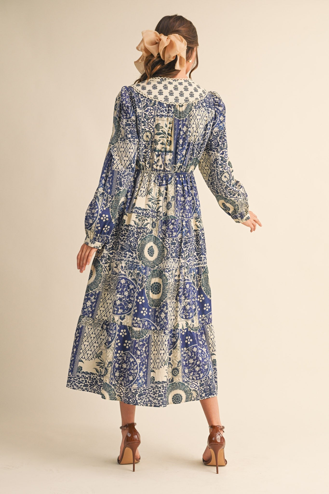 woman wearing a patterned blue maxi dress with puff sleeves and a tiered skirt, shown from the back
