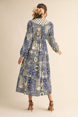 woman wearing a patterned blue maxi dress with puff sleeves and a tiered skirt, shown from the back
