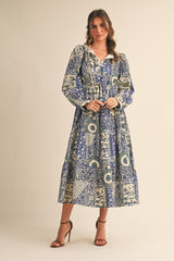 woman wearing a long-sleeve, blue and cream patterned maxi dress with a ruffled neckline and tied waist
