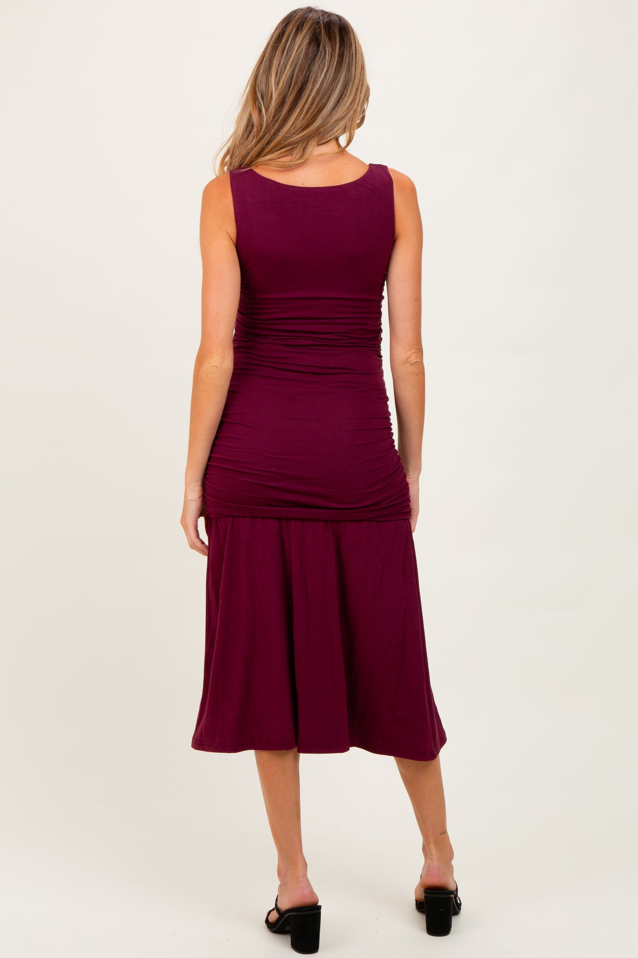 woman wearing a maroon maternity midi dress with ruching at the bodice and back, featuring a flared skirt