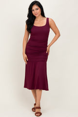 woman wearing a burgundy sleeveless ruched midi dress and brown strappy sandals