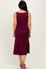 woman wearing a burgundy sleeveless ruching dress with a flared hem and visible back detail