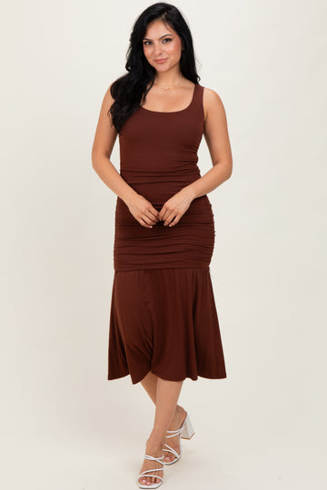 woman wearing a brown sleeveless midi dress with ruching details and a flared hem