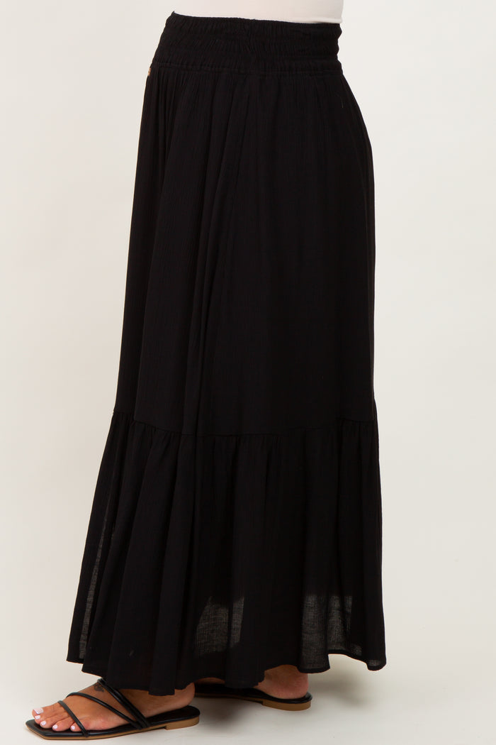 woman wearing a black maternity maxi skirt with a tiered design and elastic waistband