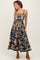 woman wearing a navy blue floral midi dress with spaghetti straps and a fitted bodice, styled with heeled sandals