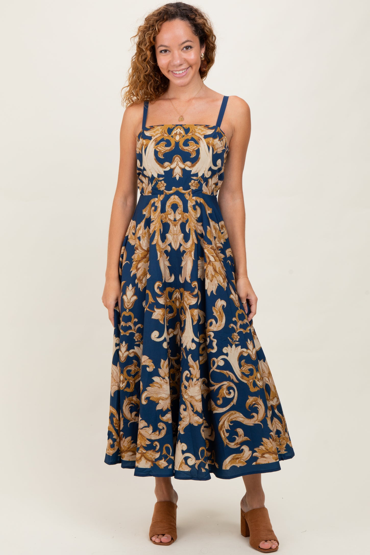 woman wearing a navy blue floral print midi dress with spaghetti straps and a fitted bodice