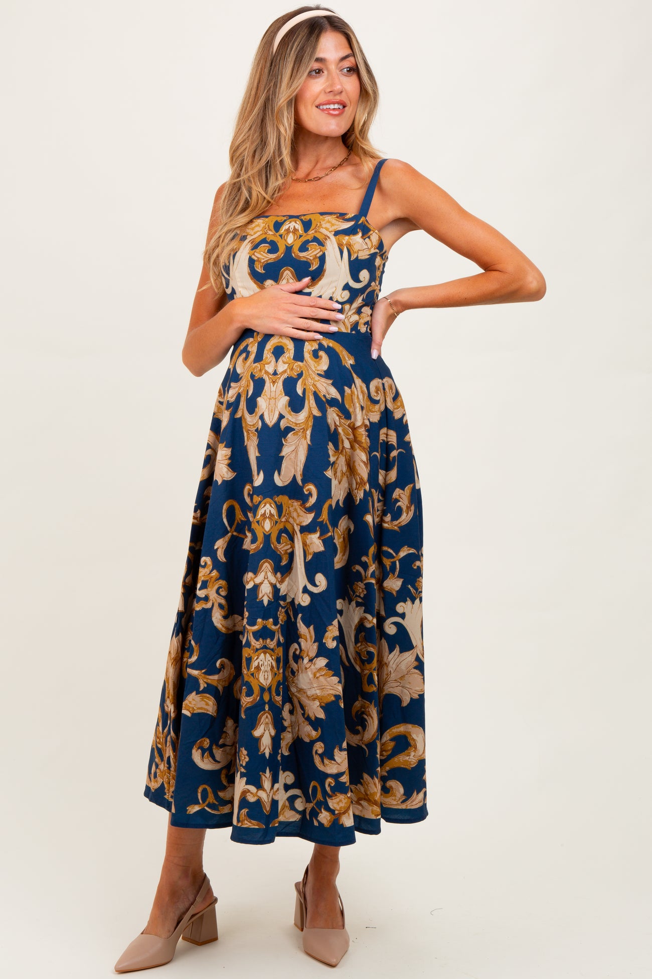 woman wearing a navy blue floral print maternity dress with straps and a baby bump visible