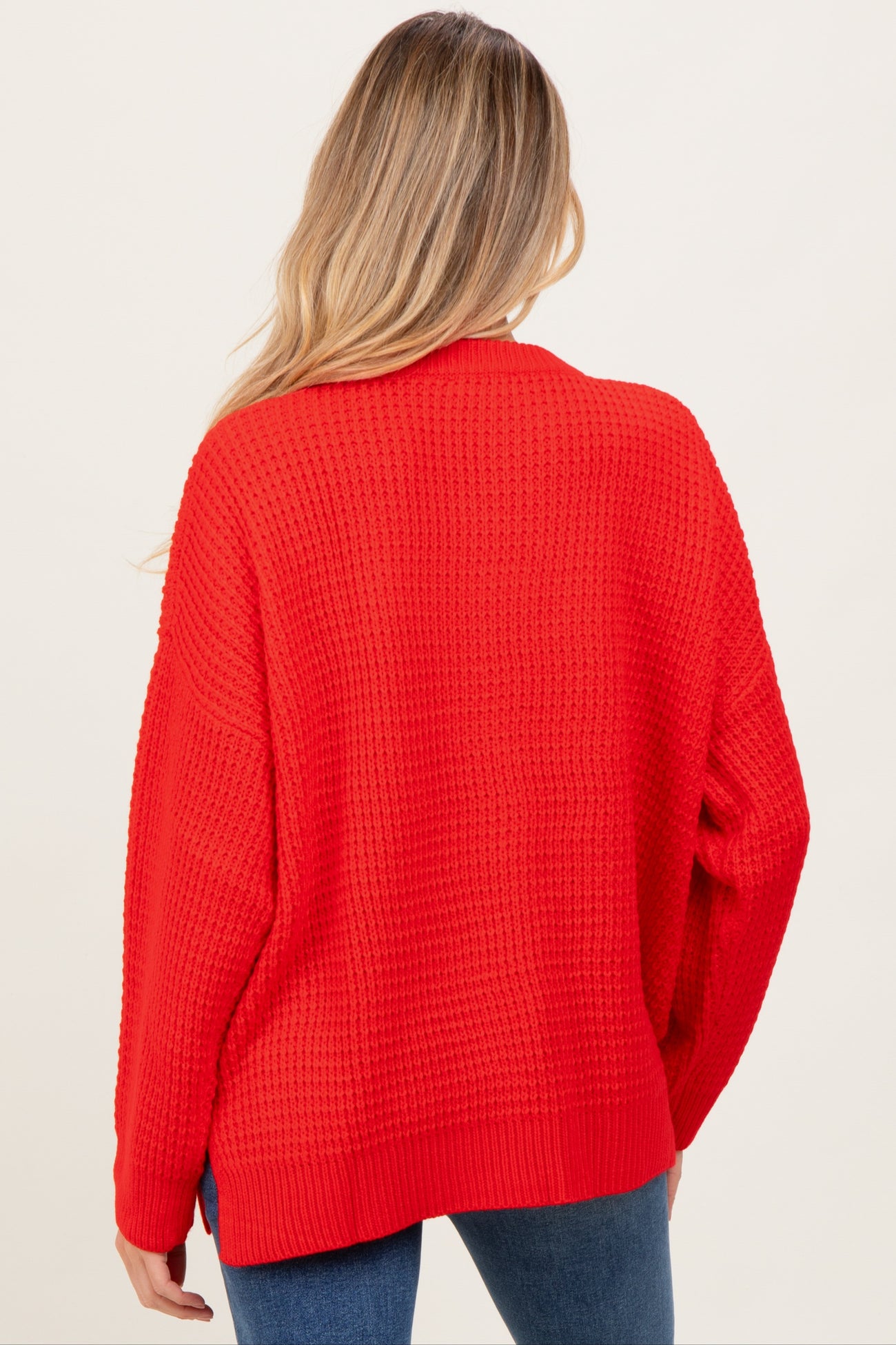 woman wearing a red oversized knit maternity sweater viewed from the back
