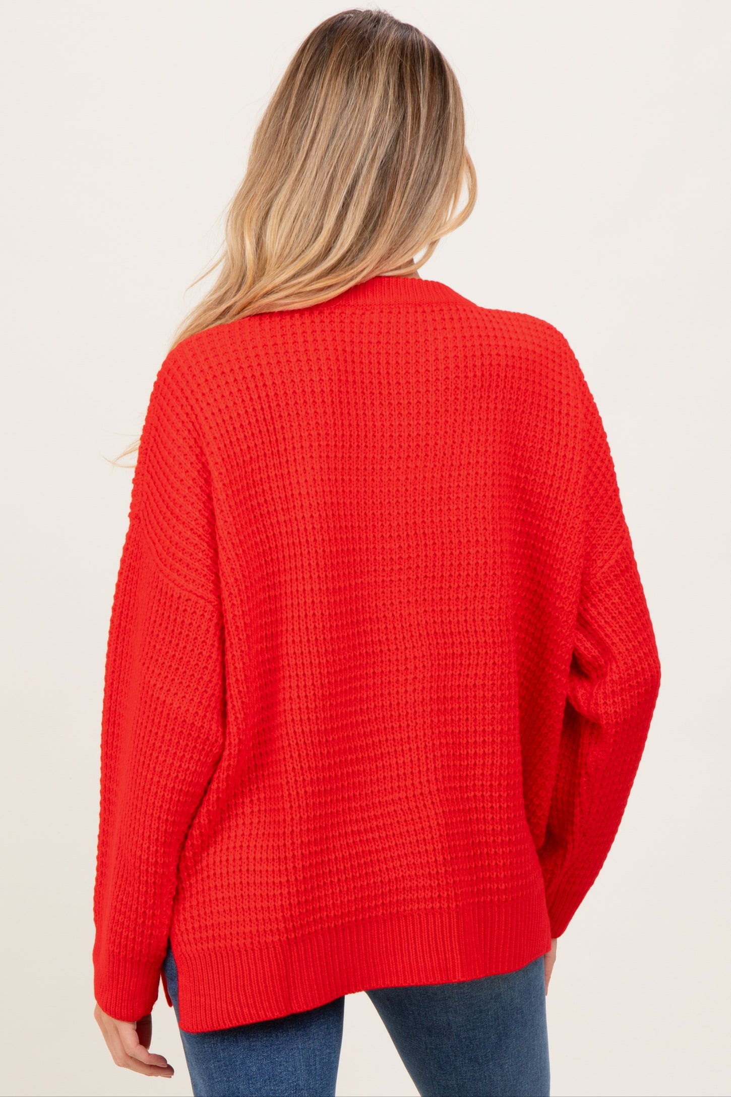 woman wearing a red oversized knit maternity sweater viewed from the back