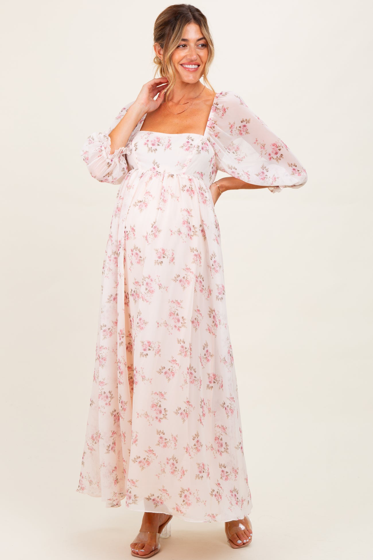 woman wearing a floral maternity maxi dress with puff sleeves and a front slit, showcasing her baby bump