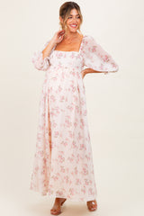 woman wearing a floral maternity maxi dress with puff sleeves and a front slit, showcasing her baby bump