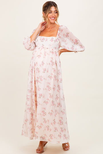 woman wearing a floral maternity maxi dress with puff sleeves and a front slit, showcasing her baby bump