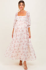 woman wearing a white floral maternity maxi dress with bell sleeves and a square neckline, showcasing her baby bump