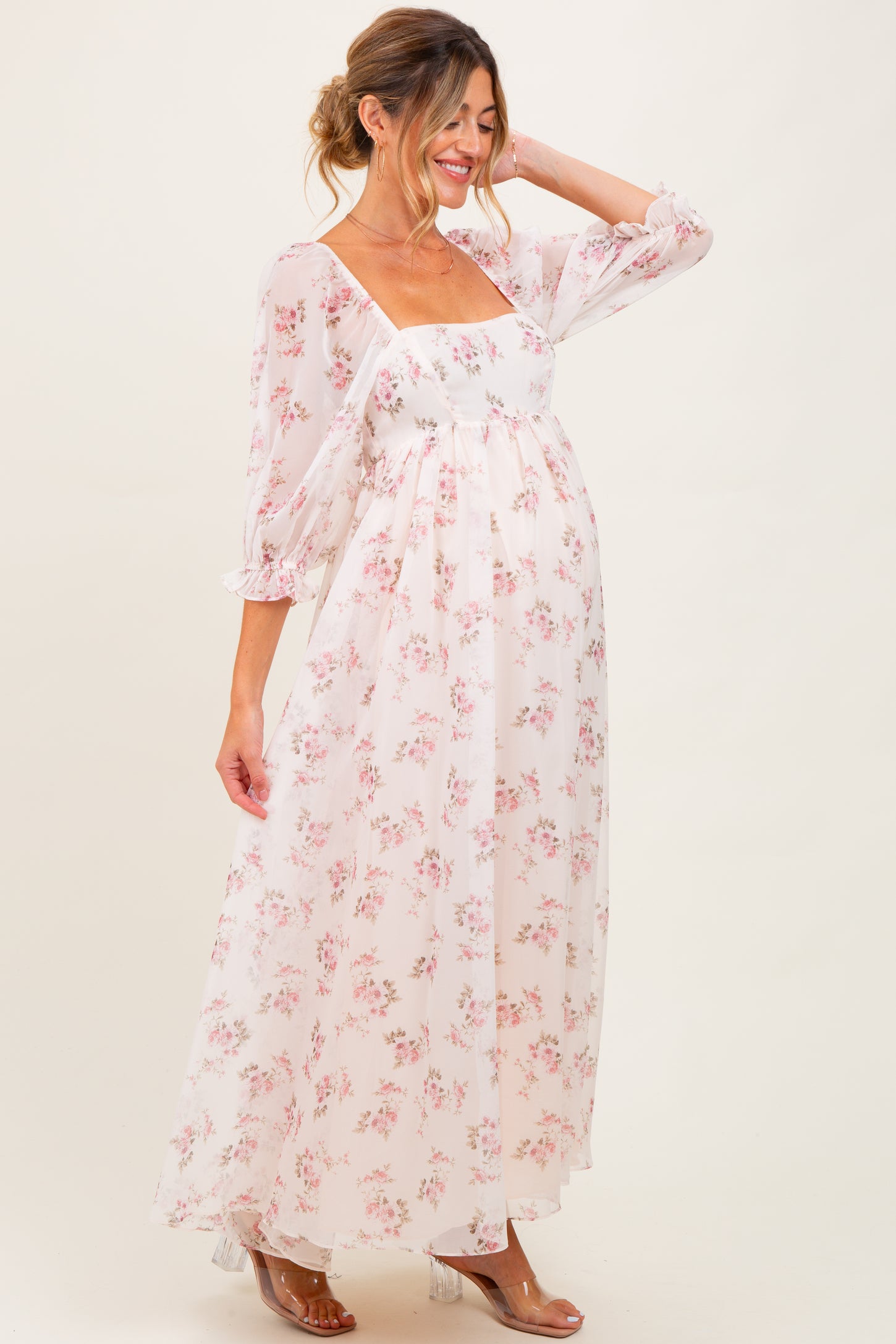 woman wearing a floral long sleeve maternity dress with a square neckline and flowing skirt, showing her baby bump