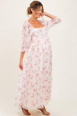 woman wearing a floral long sleeve maternity dress with a square neckline and flowing skirt, showing her baby bump