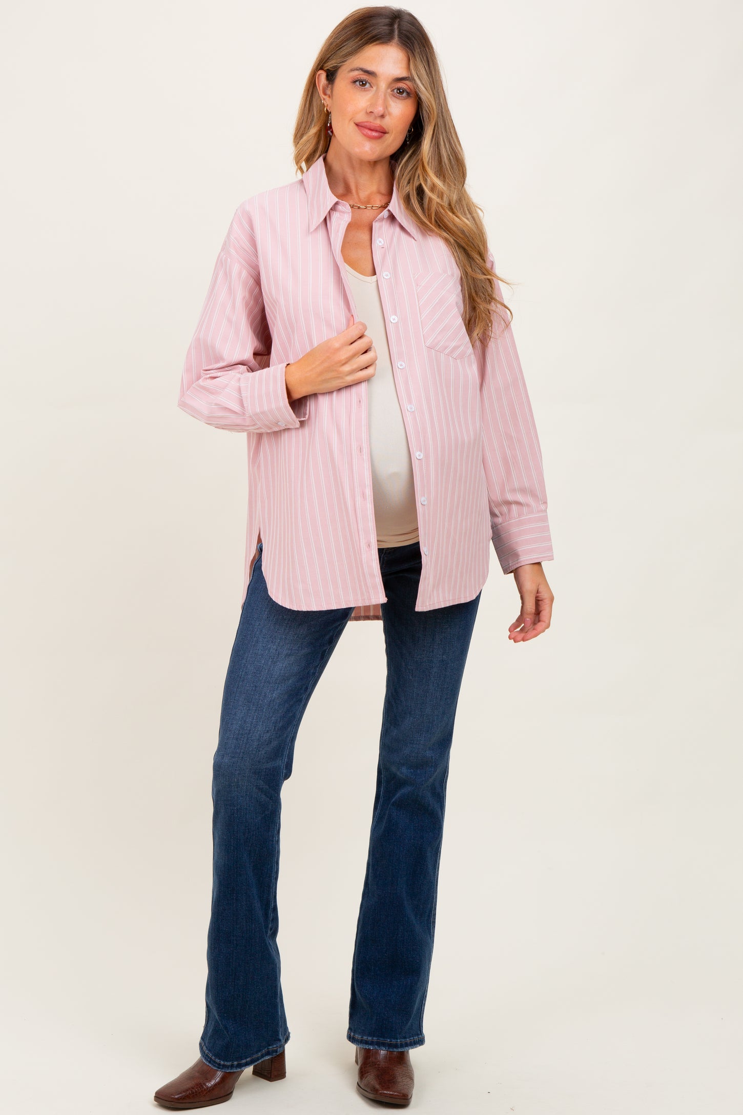woman wearing a pink and white striped maternity shirt with blue flared jeans and showing her baby bump