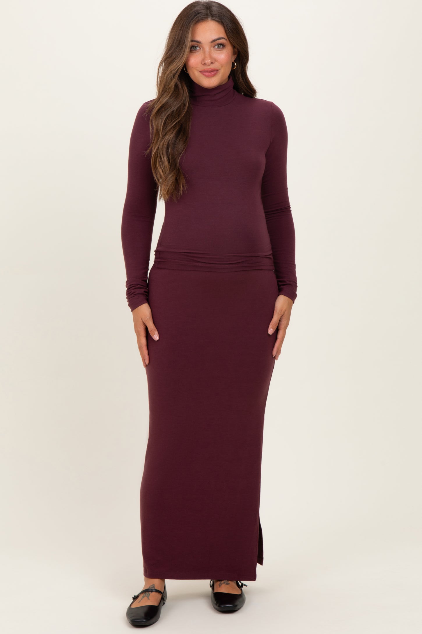 woman wearing a burgundy long sleeve maternity dress with a snug fit and side slit, showcasing her baby bump