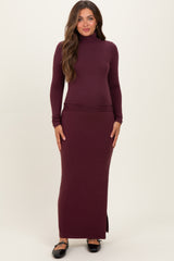 woman wearing a burgundy long sleeve maternity dress with a snug fit and side slit, showcasing her baby bump