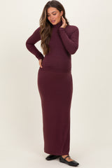 woman wearing a burgundy maternity turtleneck dress with a fitted silhouette and long sleeves, showcasing her baby bump