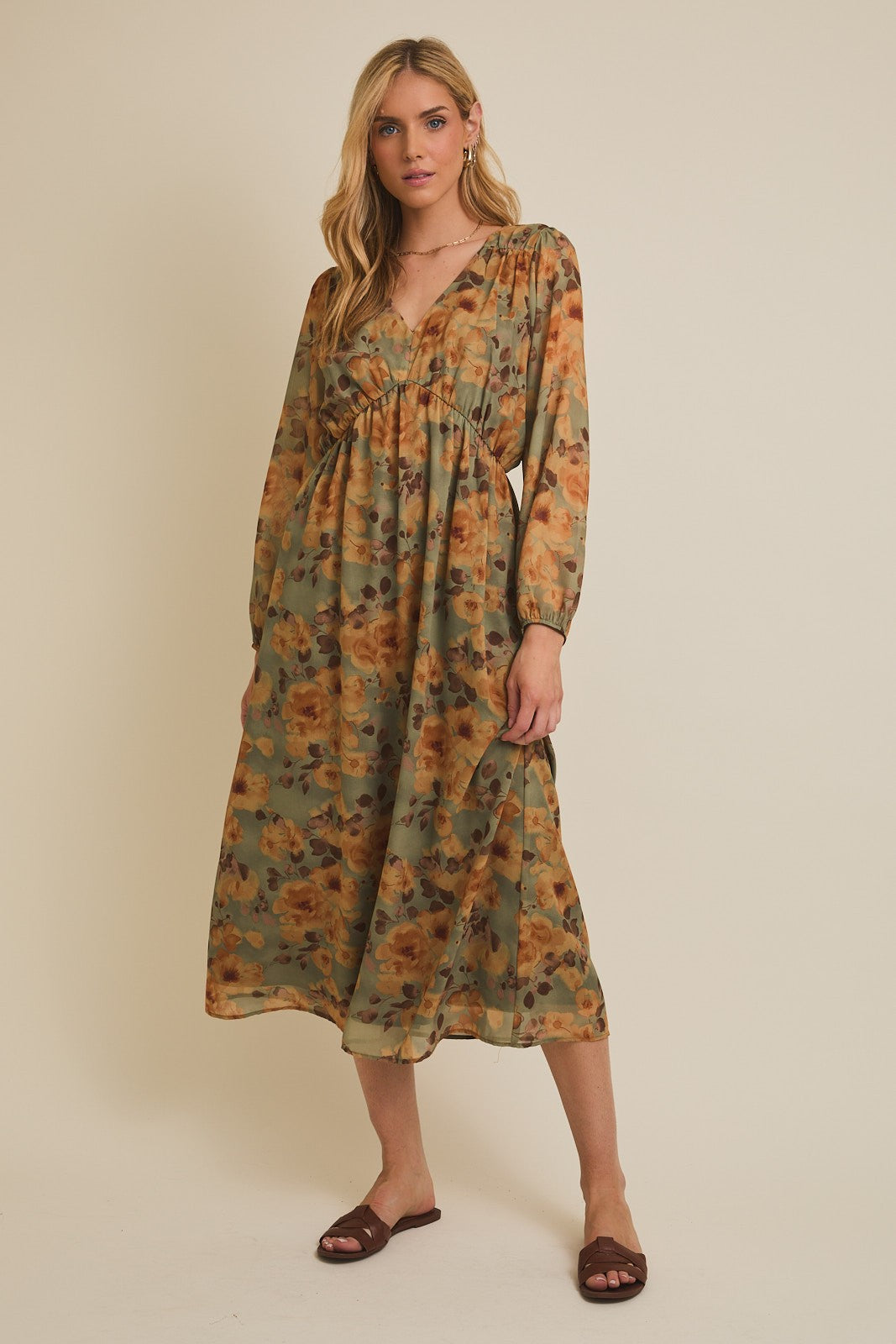woman wearing a floral green and orange maxi dress with long sleeves and a v-neckline