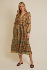 woman wearing a floral green and orange maxi dress with long sleeves and a v-neckline