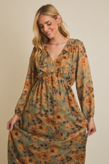 woman wearing a floral long sleeve dress in olive green with orange and brown tones, featuring a deep v-neck and gathered waist
