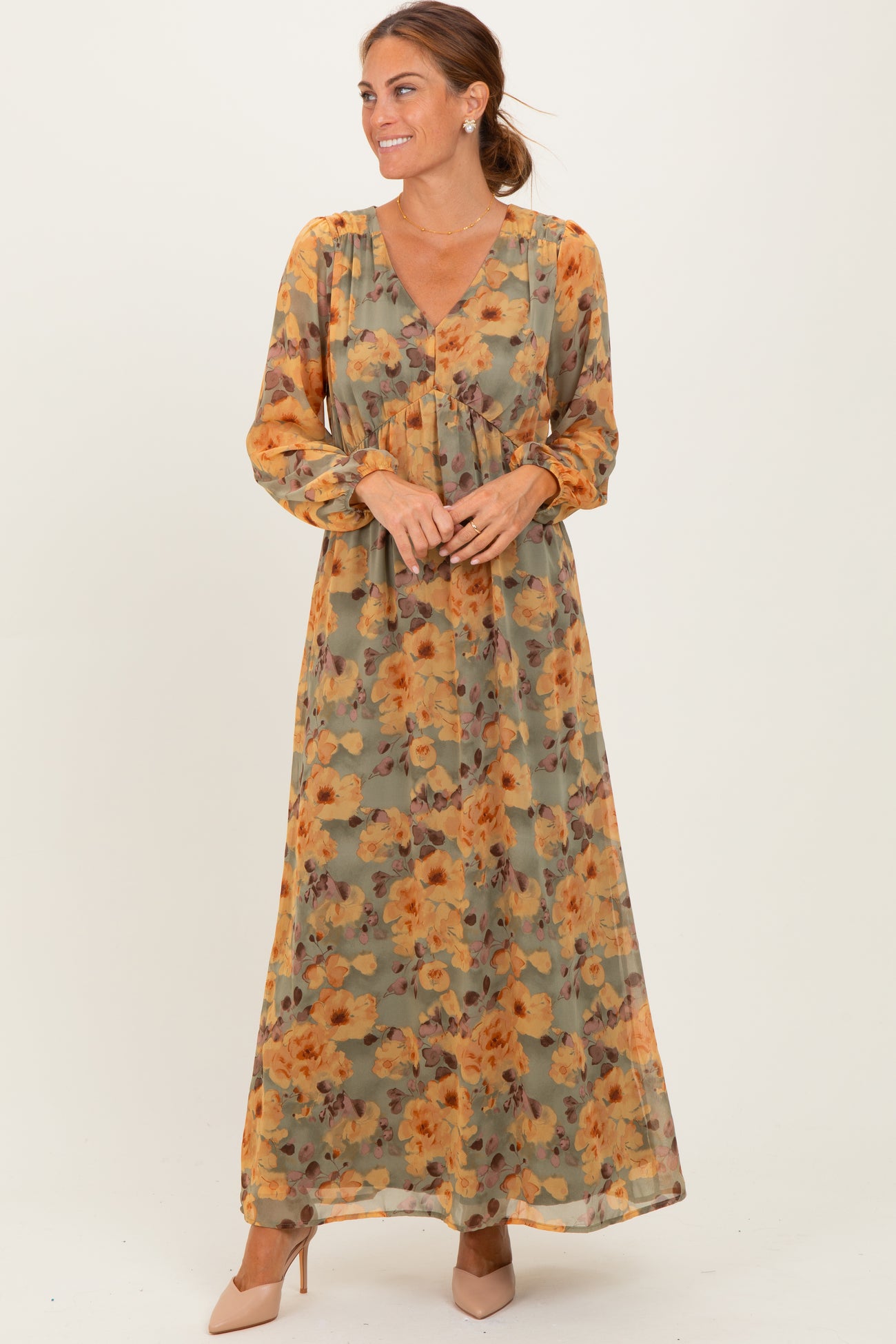 woman wearing a long floral maxi dress in earthy tones with a v-neck and long sleeves