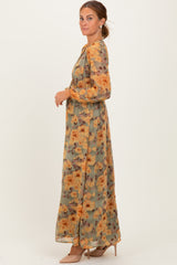 woman wearing a long floral maxi dress with orange and yellow flowers on a green background and nude heels