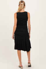 woman wearing a black sleeveless maternity dress with a fitted top and flowy skirt, showing a baby bump