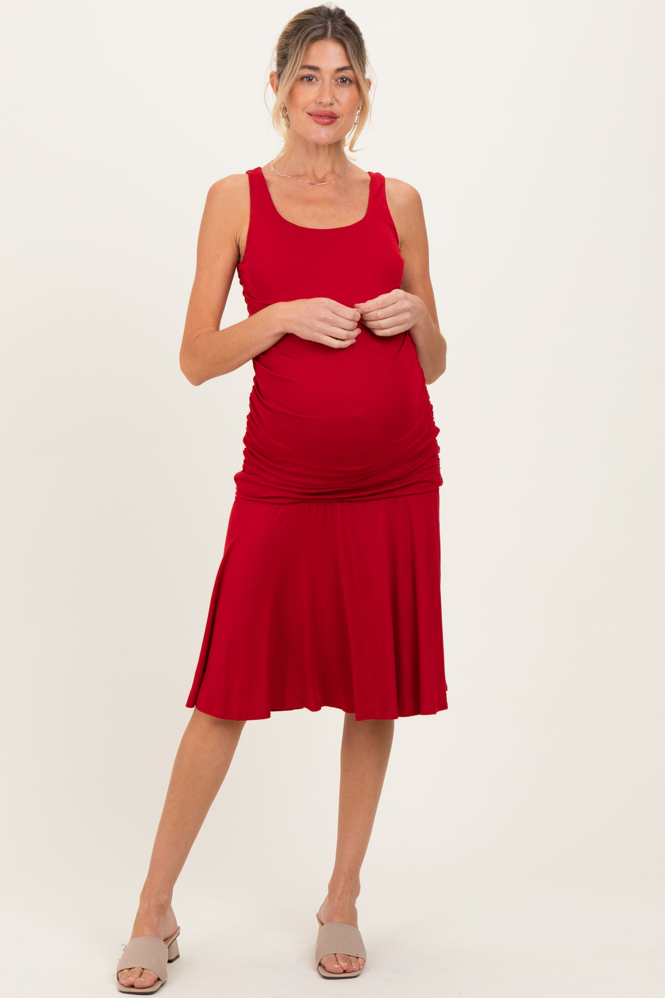 woman wearing a red maternity dress with ruched sides and a flared skirt, showing her baby bump