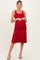 woman wearing a red maternity dress with ruched sides and a flared skirt, showing her baby bump