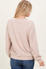 woman wearing a light pink ribbed sweater with long sleeves and a relaxed fit, viewed from the back