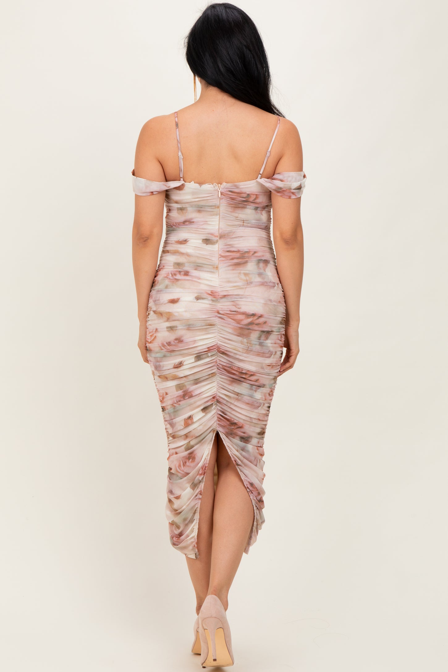 woman wearing a floral print ruched midi dress with off-the-shoulder straps and a back slit