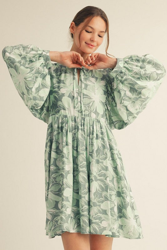 woman wearing a green floral print puff sleeve dress with a cinched waist and a keyhole neckline