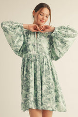 woman wearing a green floral print puff sleeve dress with a cinched waist and a keyhole neckline