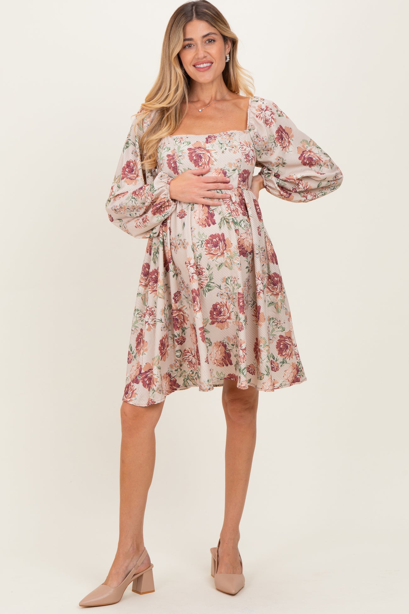 woman wearing a floral print maternity dress with long puff sleeves and a square neckline, highlighting her baby bump