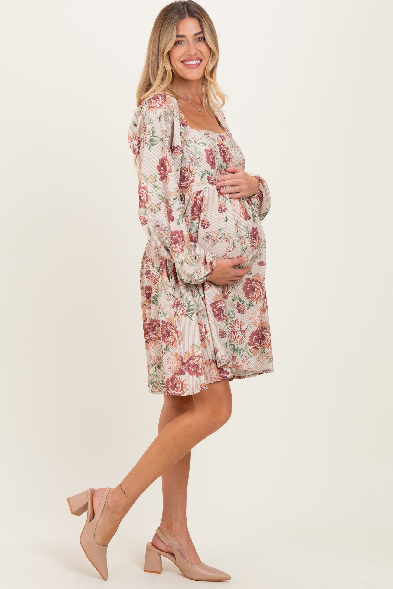 woman wearing a floral maternity dress with puff sleeves and holding her baby bump