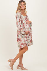 woman wearing a floral maternity dress with puff sleeves and holding her baby bump