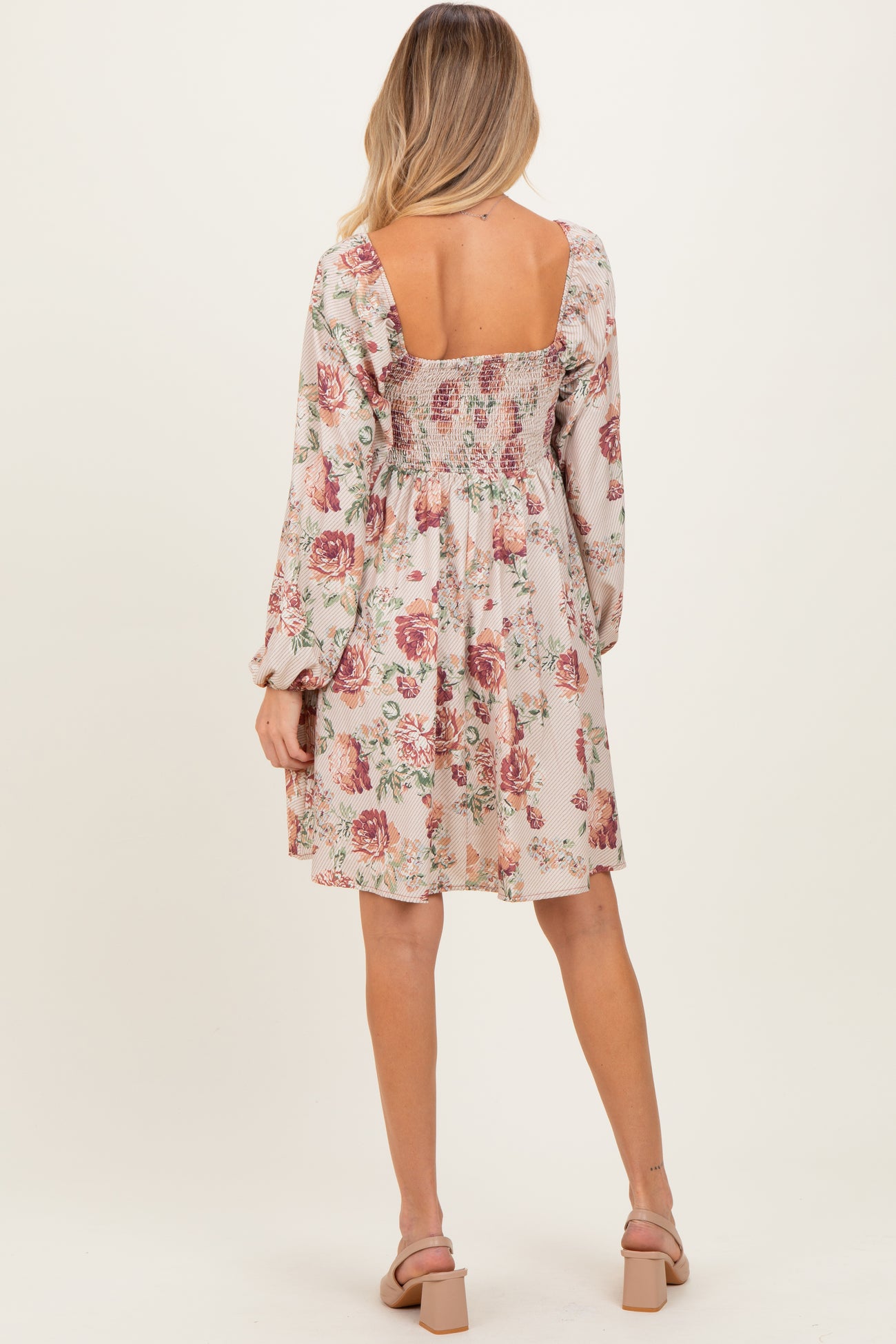 woman wearing a floral print smocked back maternity dress with long sleeves and a flowy skirt